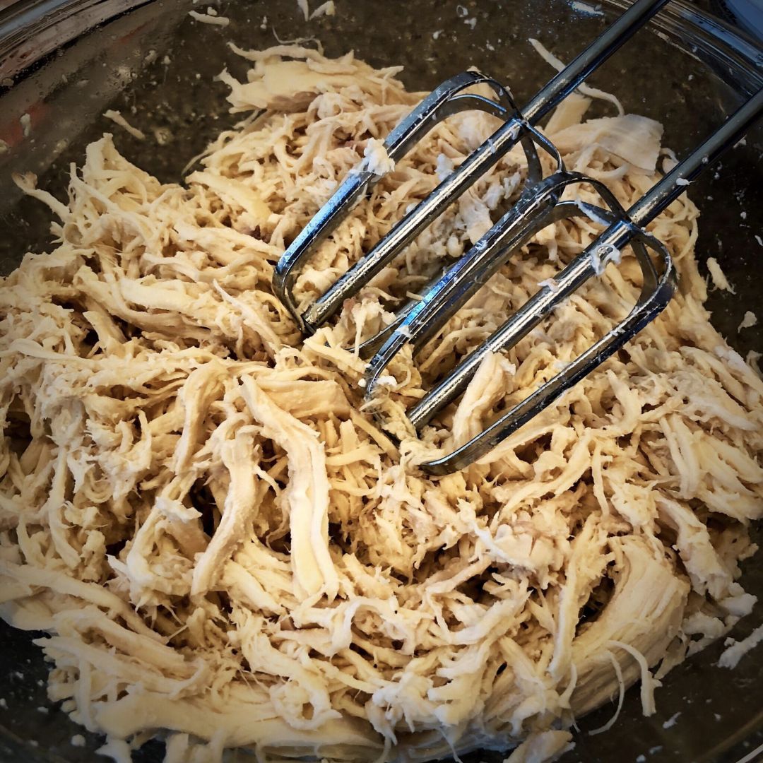 Mixer beaters in shredded chicken; illustrative archive photograph, meat temperature not verified.