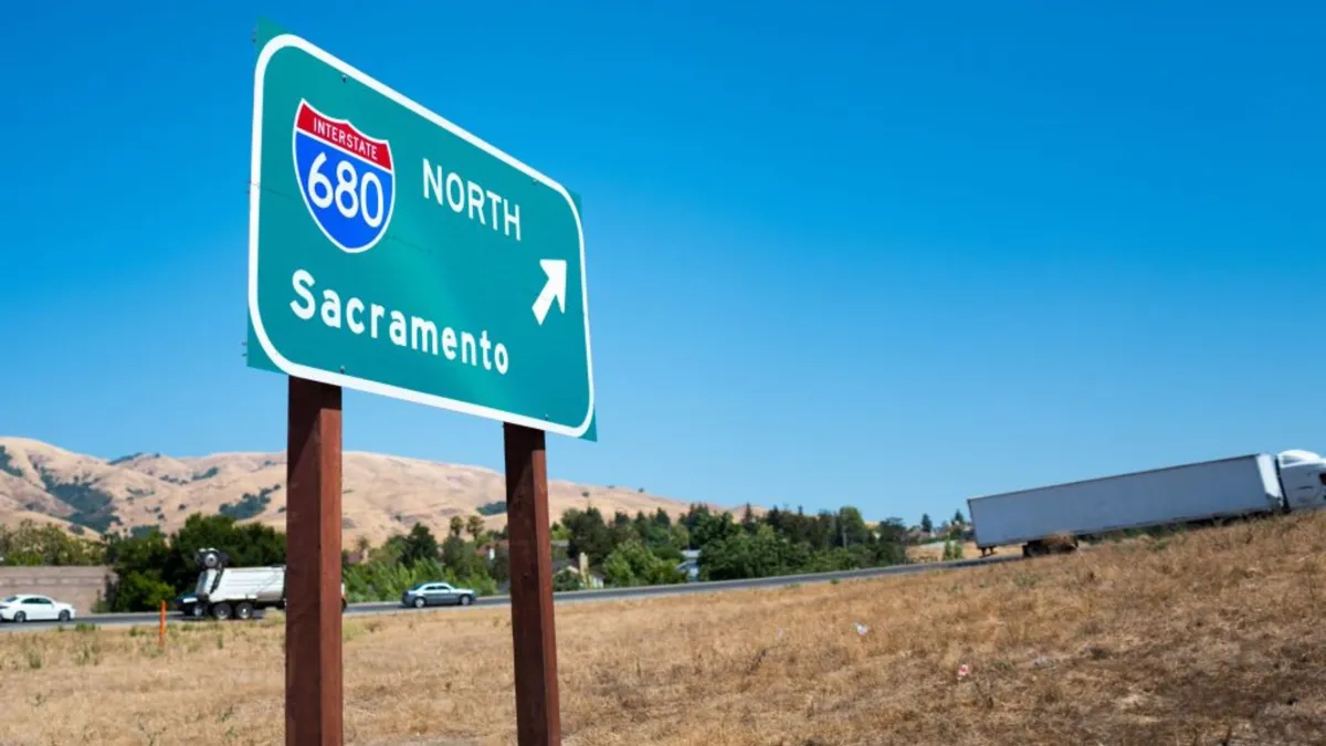 A large green traffic sign advertising Sacramento near a large highway