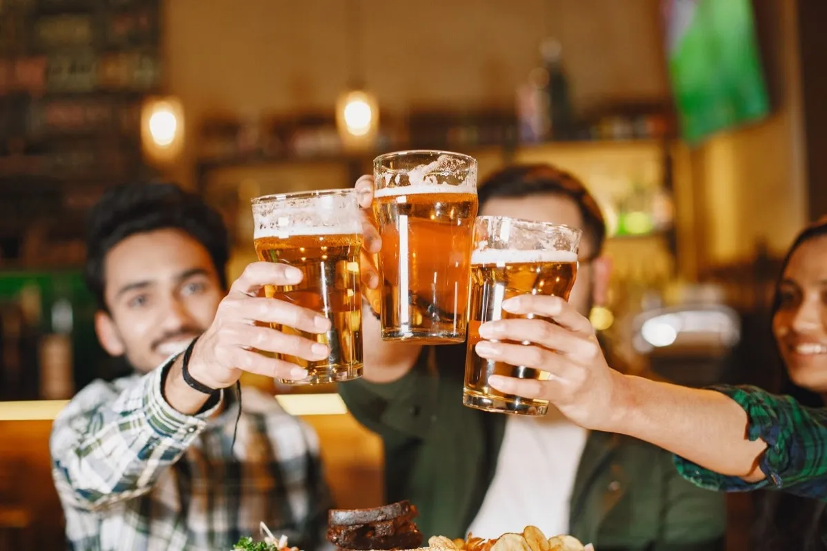 A group of friends cheers their beers as they spend time together in a bar