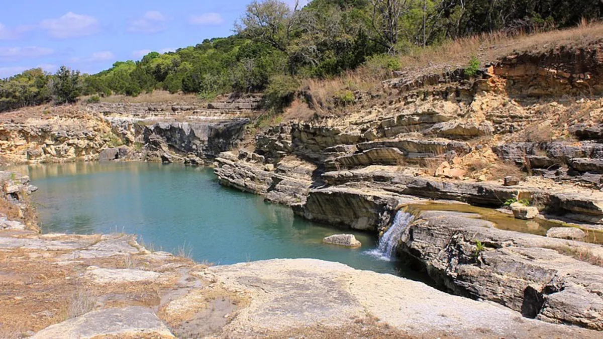 A small lake surrounded by rocky shore and green bushes