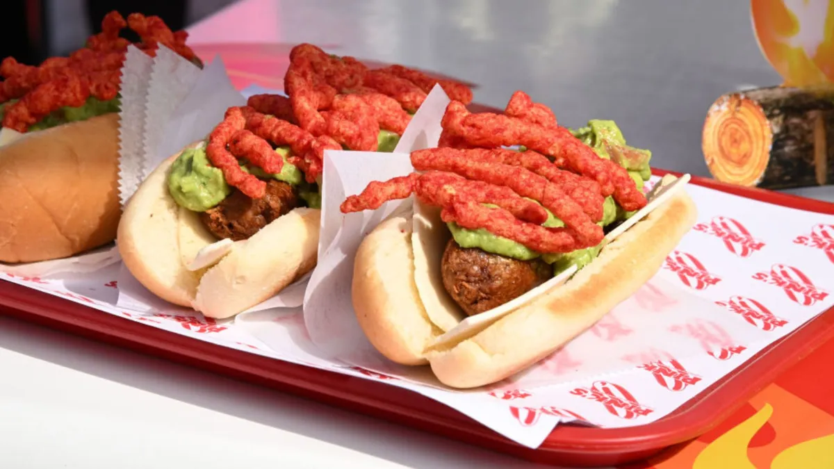 A tray with two hot dogs with guacamole and cheetos on top