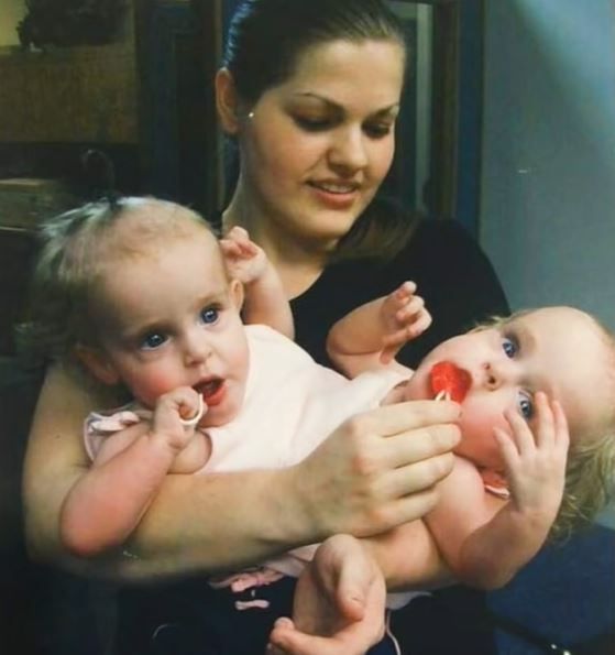 An adult holding the Herrin twins as young children