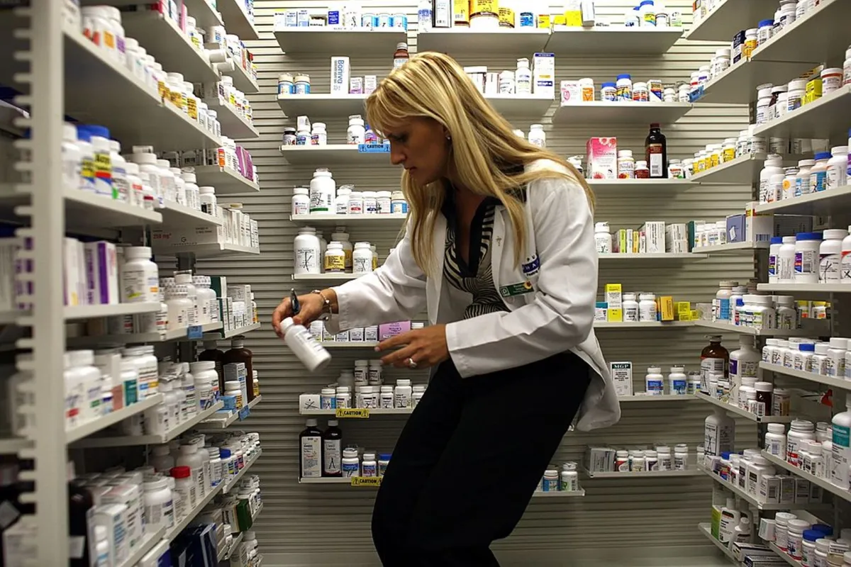 A Publix Supermarket pharmacy manager retrieves a bottle of antibiotics from the shelf