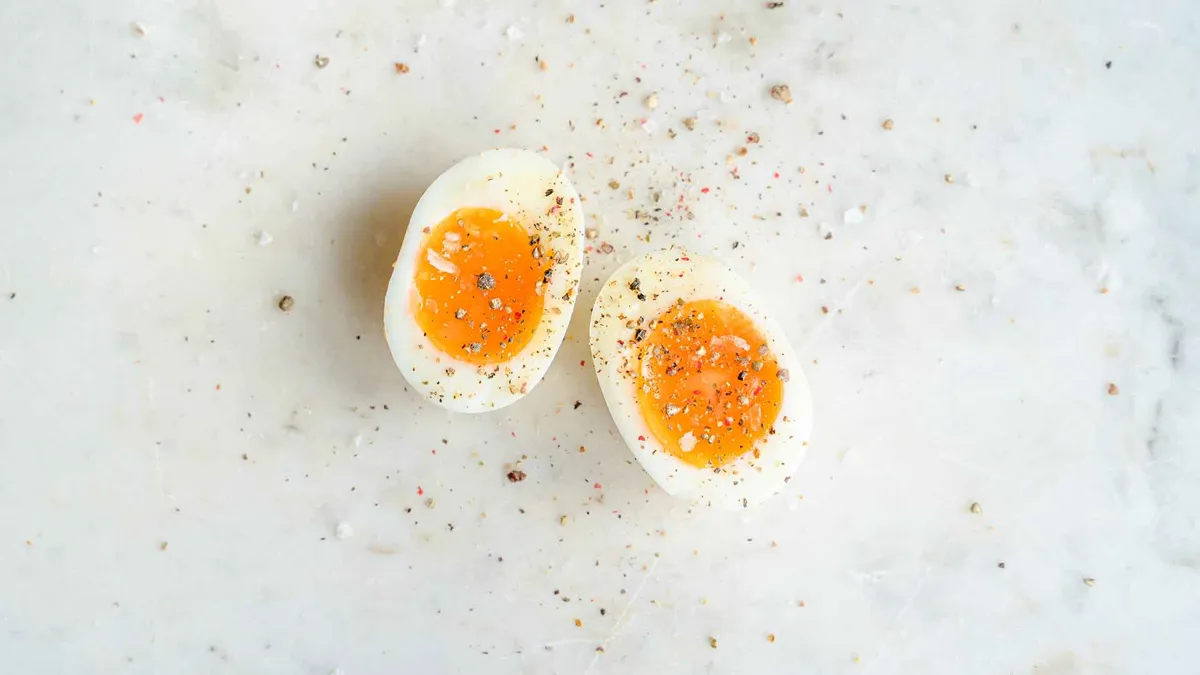 A spiced soft boiled egg sits on a marble tabletop