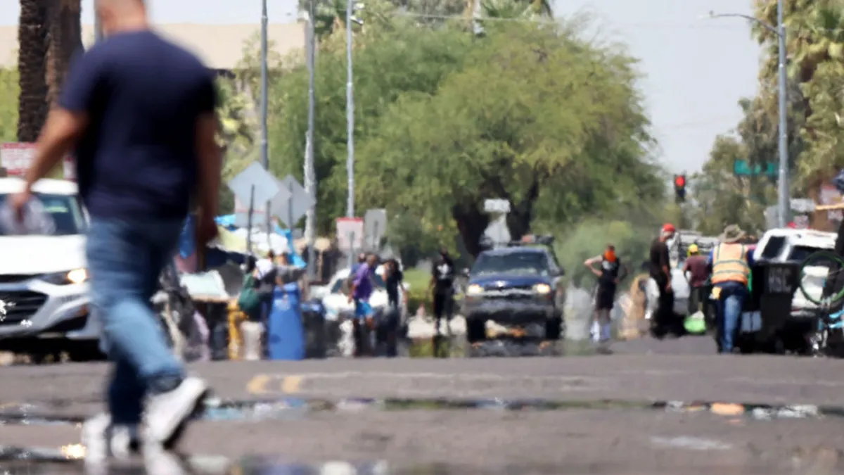 A man walking past a street hazy with heat