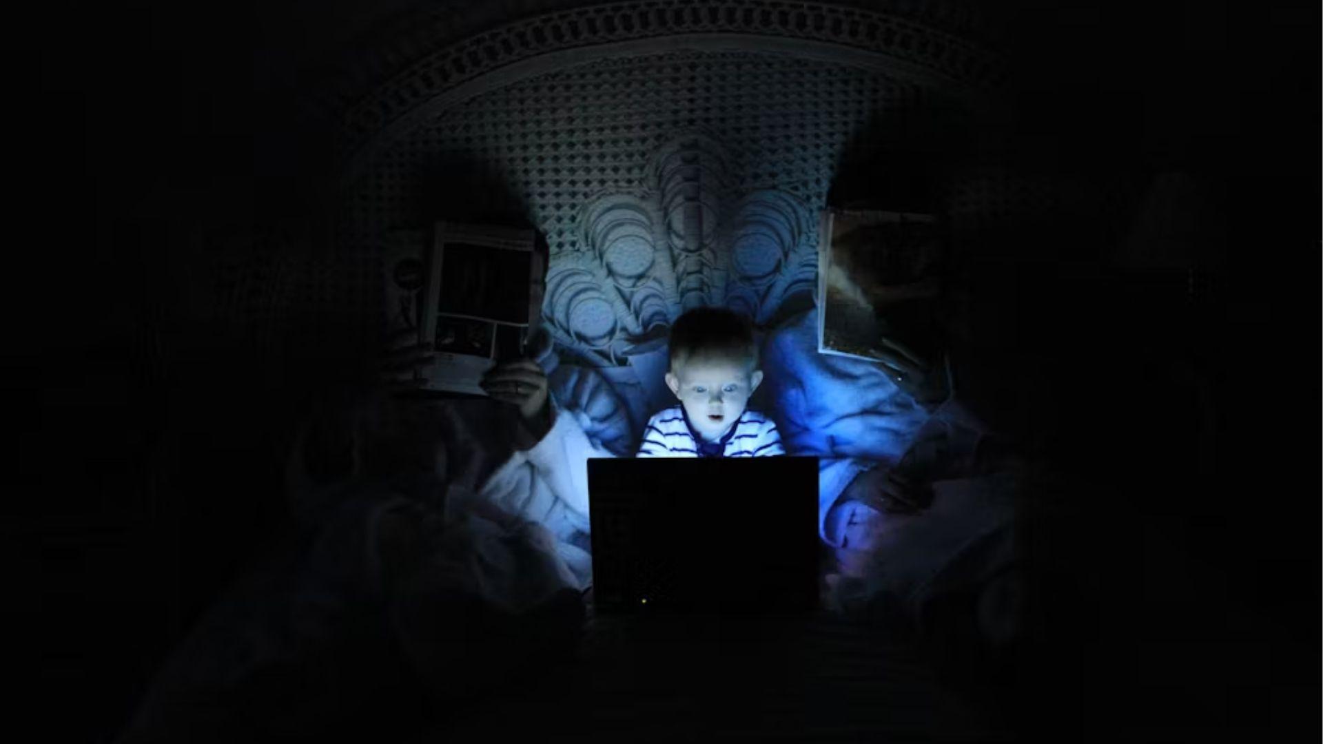 A person lit by a laptop screen; illustrative archive photograph, not an identified affected child.