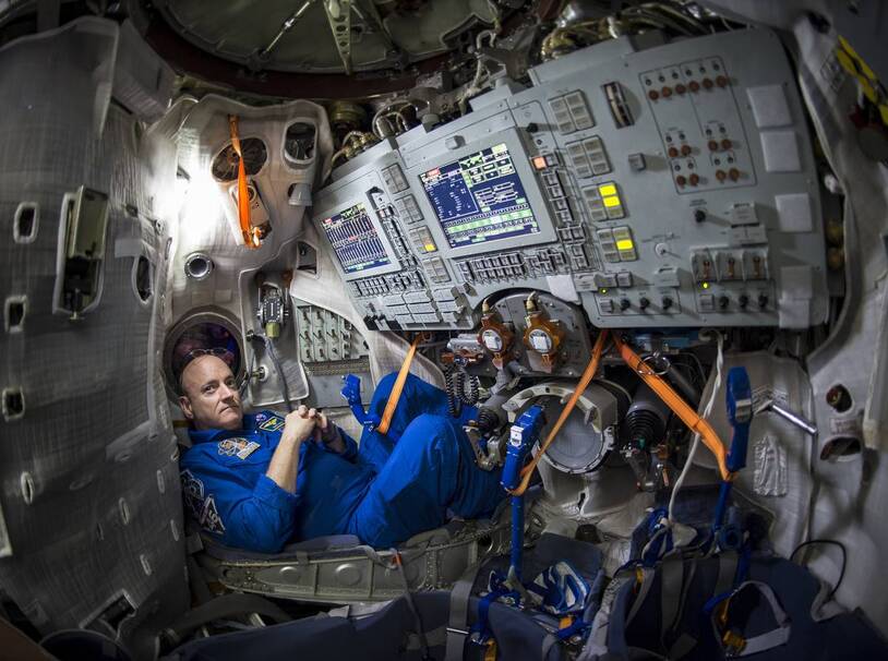 A crew member surrounded by equipment inside a capsule