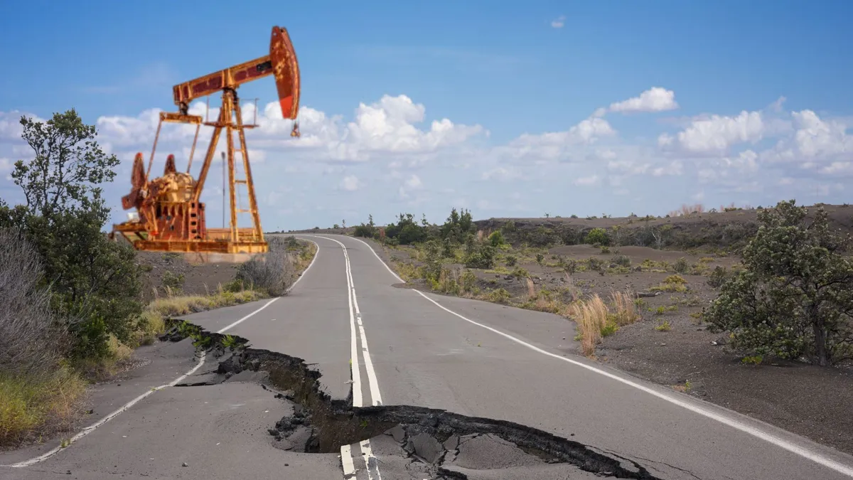 A road with a large crack in it with an oil pump in the background
