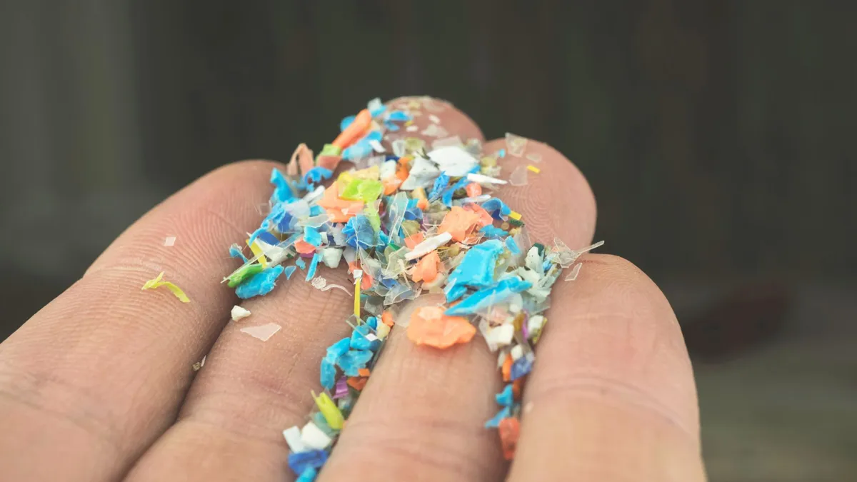 A man holding his fingers out filled with small plastic pieces