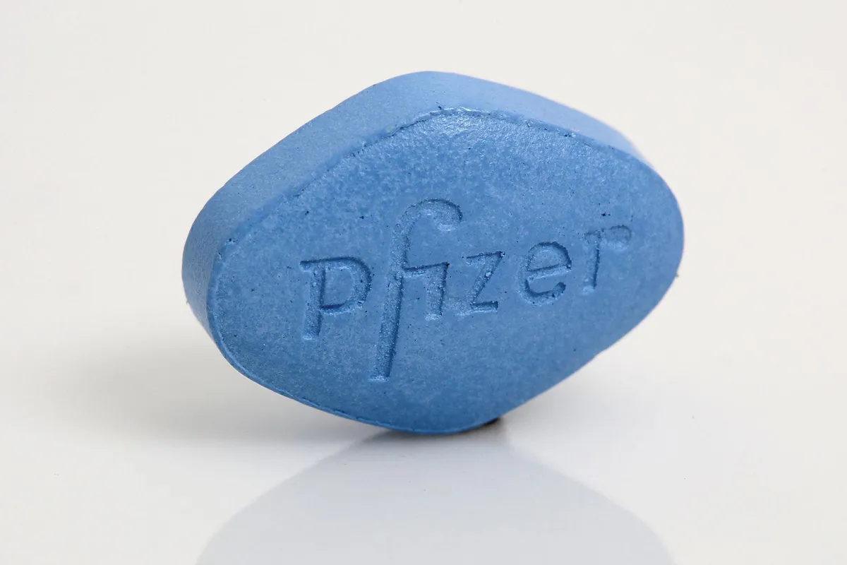 A close-up of a blue, diamond-shaped pill with "Pfizer" engraved on one side, indicating a Viagra tablet manufactured by Pfizer