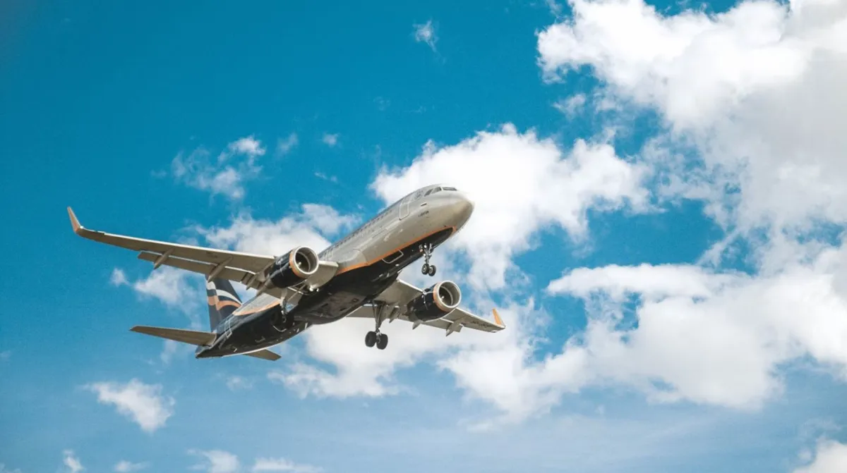 A plane taking off into a blue sky with clouds.