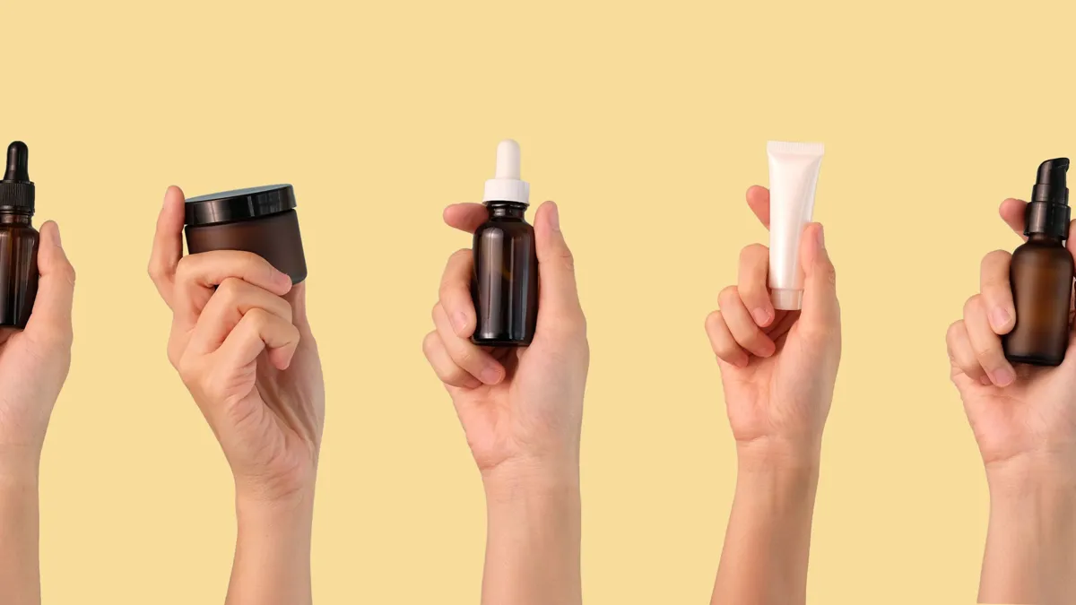 Hands holding various skin care bottles