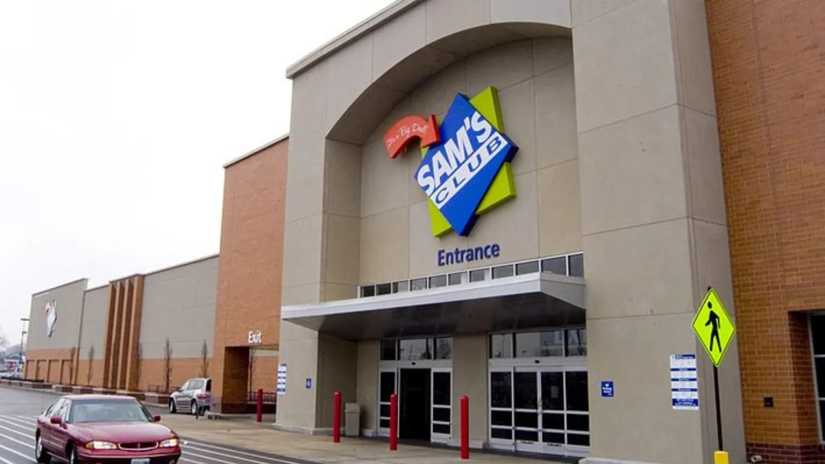 The exterior of a large department store. A red car drives in front on the street