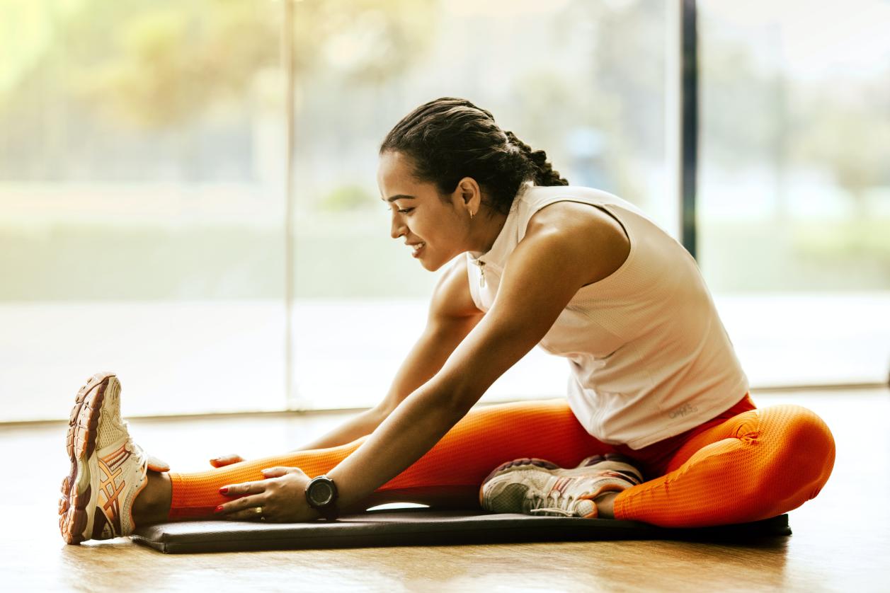 A woman stretching one leg while seated on the floor