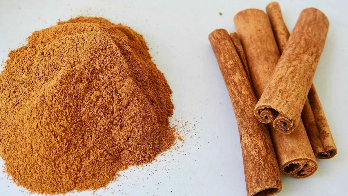 Ground cinnamon next to cinnamon sticks