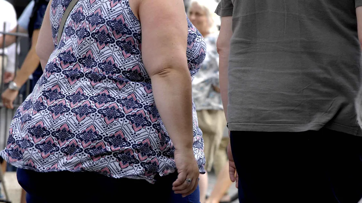 two larger people walking with back turned to camera