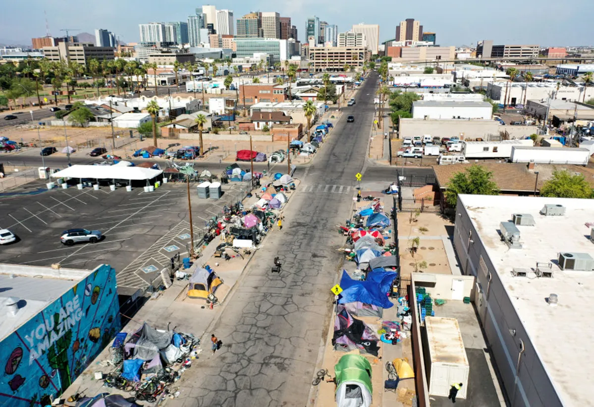 An aerial view of people walking past a homeless encampment in the afternoon heat on July 21, 2022 in Phoenix, Arizona