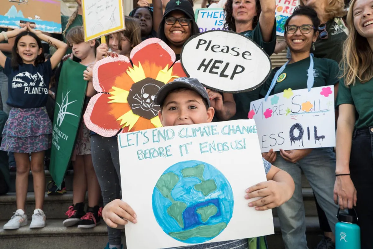 Several children hold homemade signs at a climate change protest