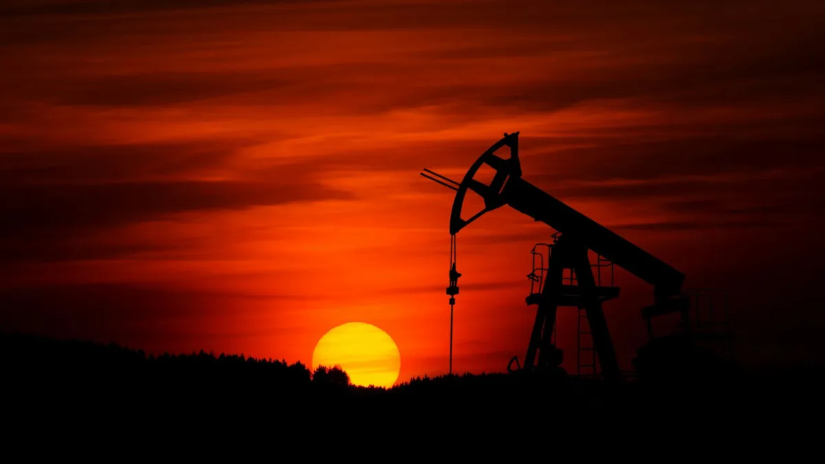 A large oil drill set against a red sunset