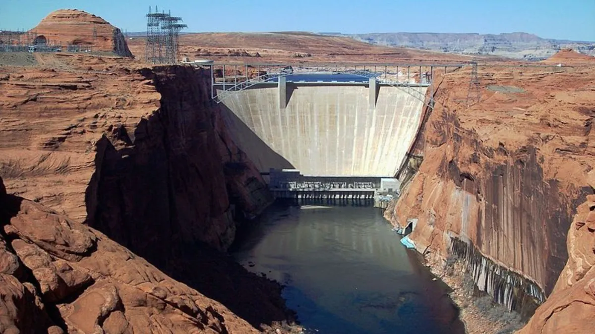 An aerial view of a large cement dam between a large red rock valley