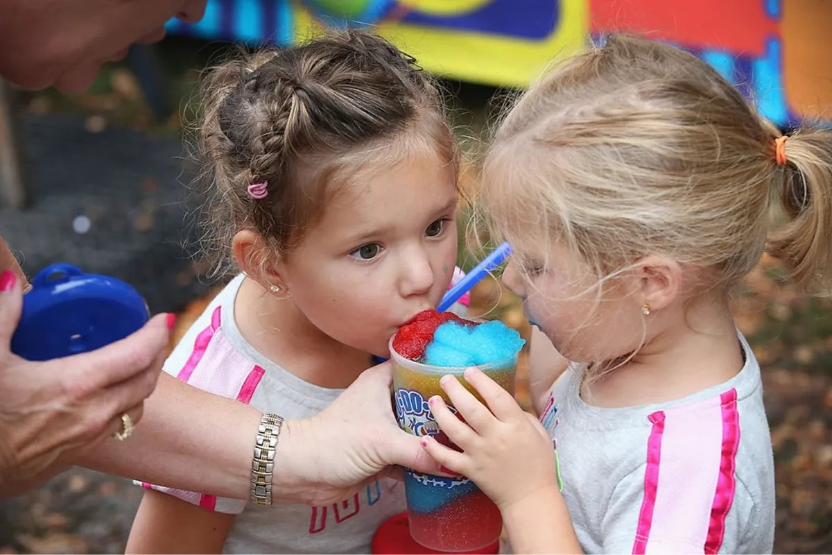 Two young girls share a slushie at a state fair in Iowa