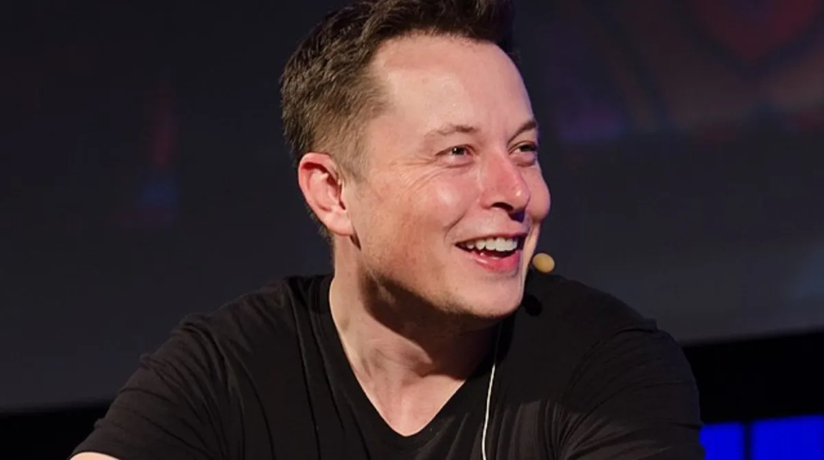 Elon Musk with a mic on his face wearing a black shirt.