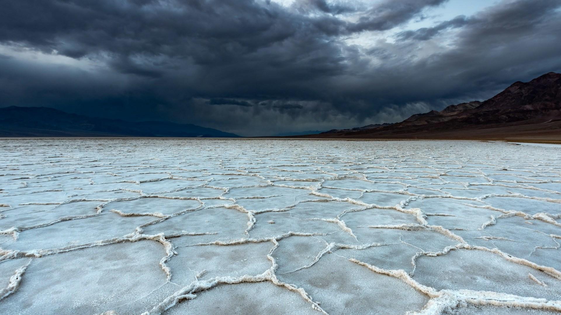 Cracked ground under storm clouds; illustrative archive landscape.