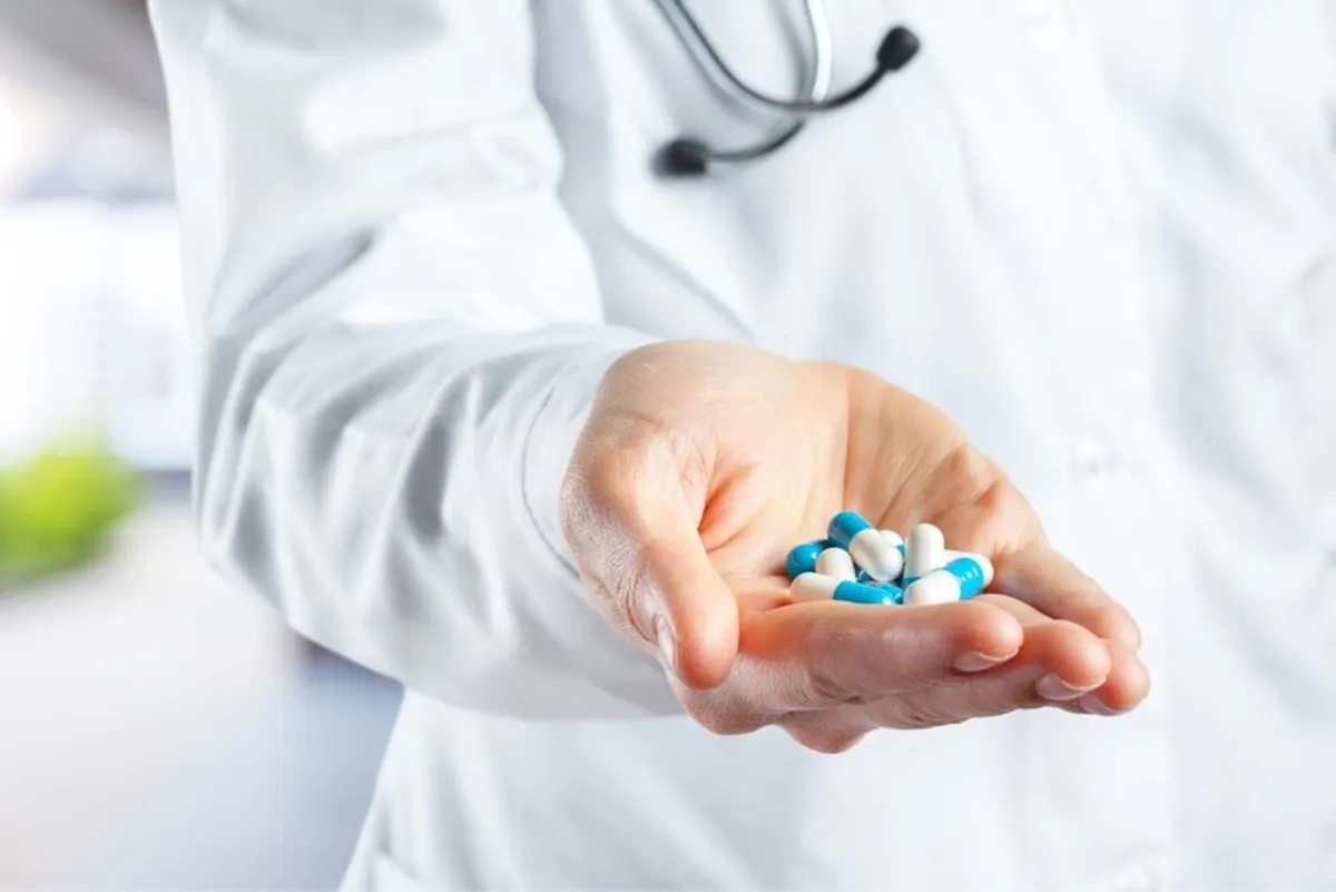 Doctor holding out hand full of blue and white capsules