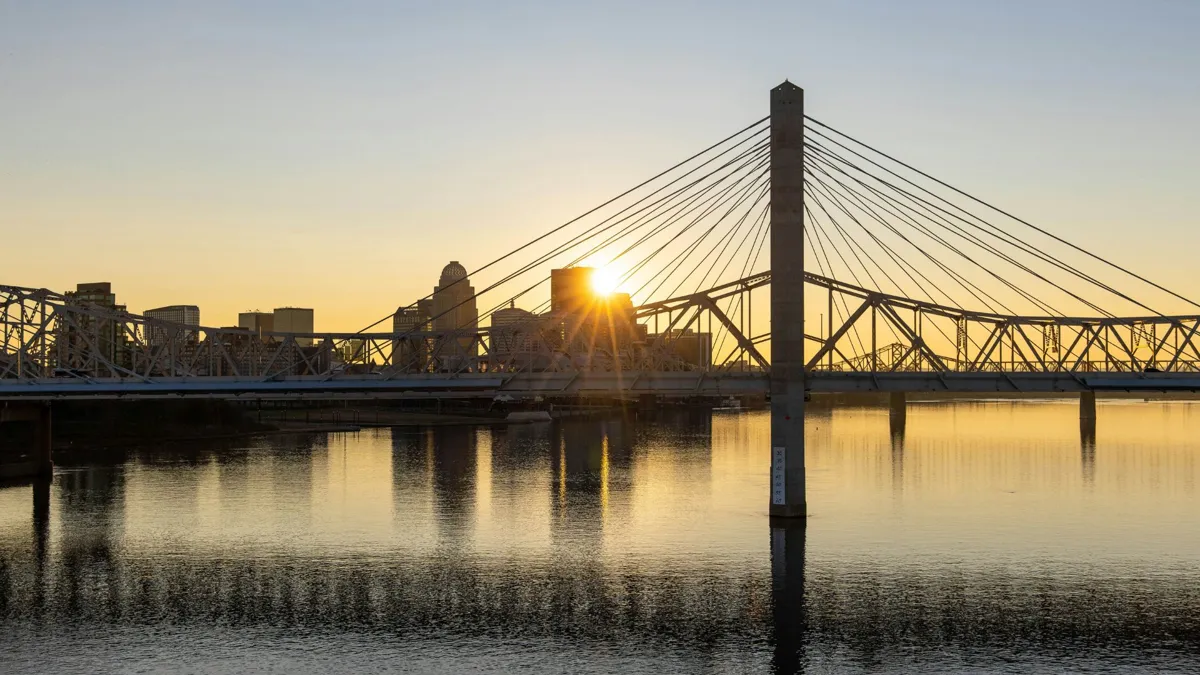 A view of a large bridge in front of a city at sunset