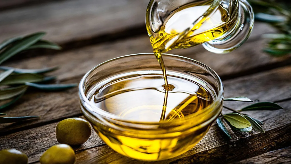 Pouring olive oil from a glass container into a bowl